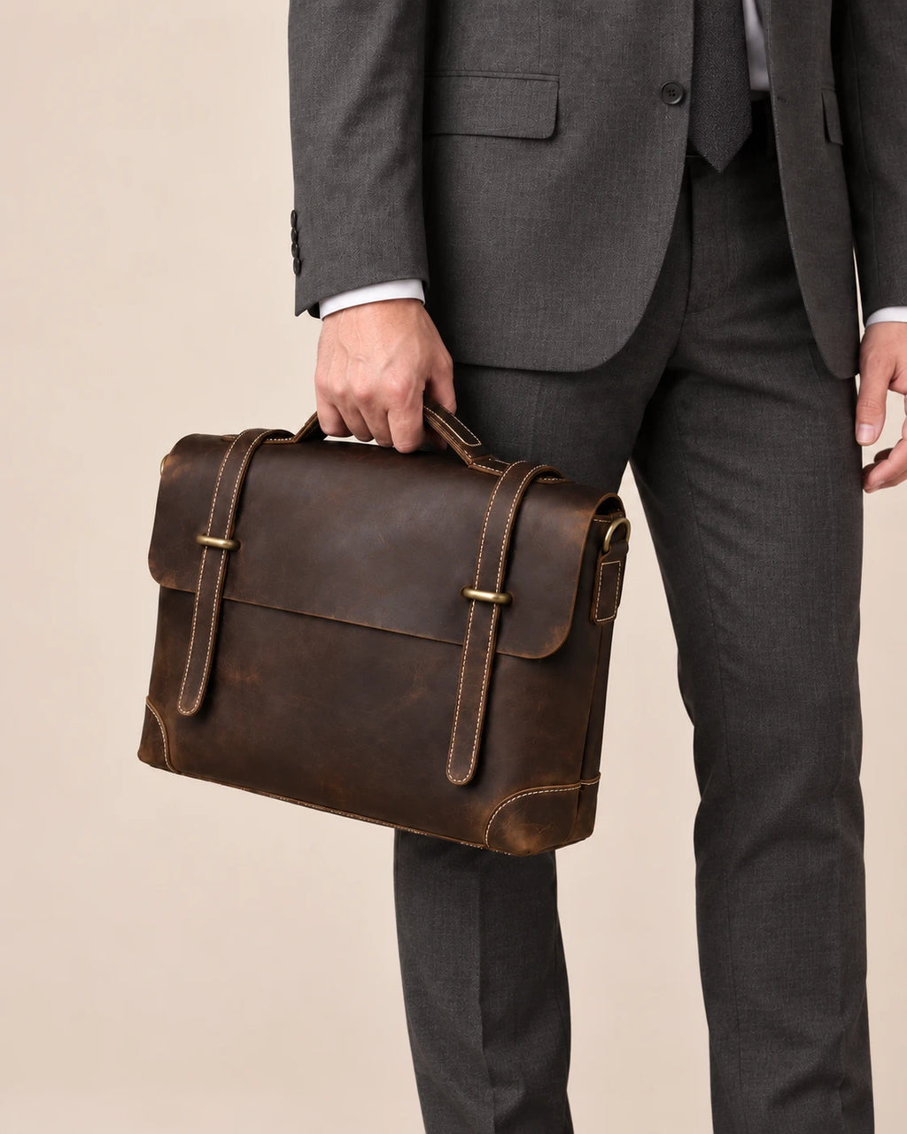 Sacoche en cuir brun foncé à lanière portée à la main