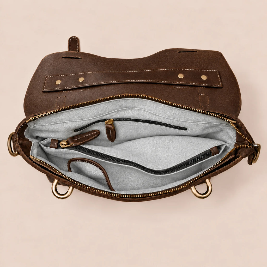 Intérieur de la sacoche en cuir brun foncé à lanière, poche zippée et compartiment ordinateur