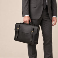 Sacoche en cuir noir à lanière portée à la main