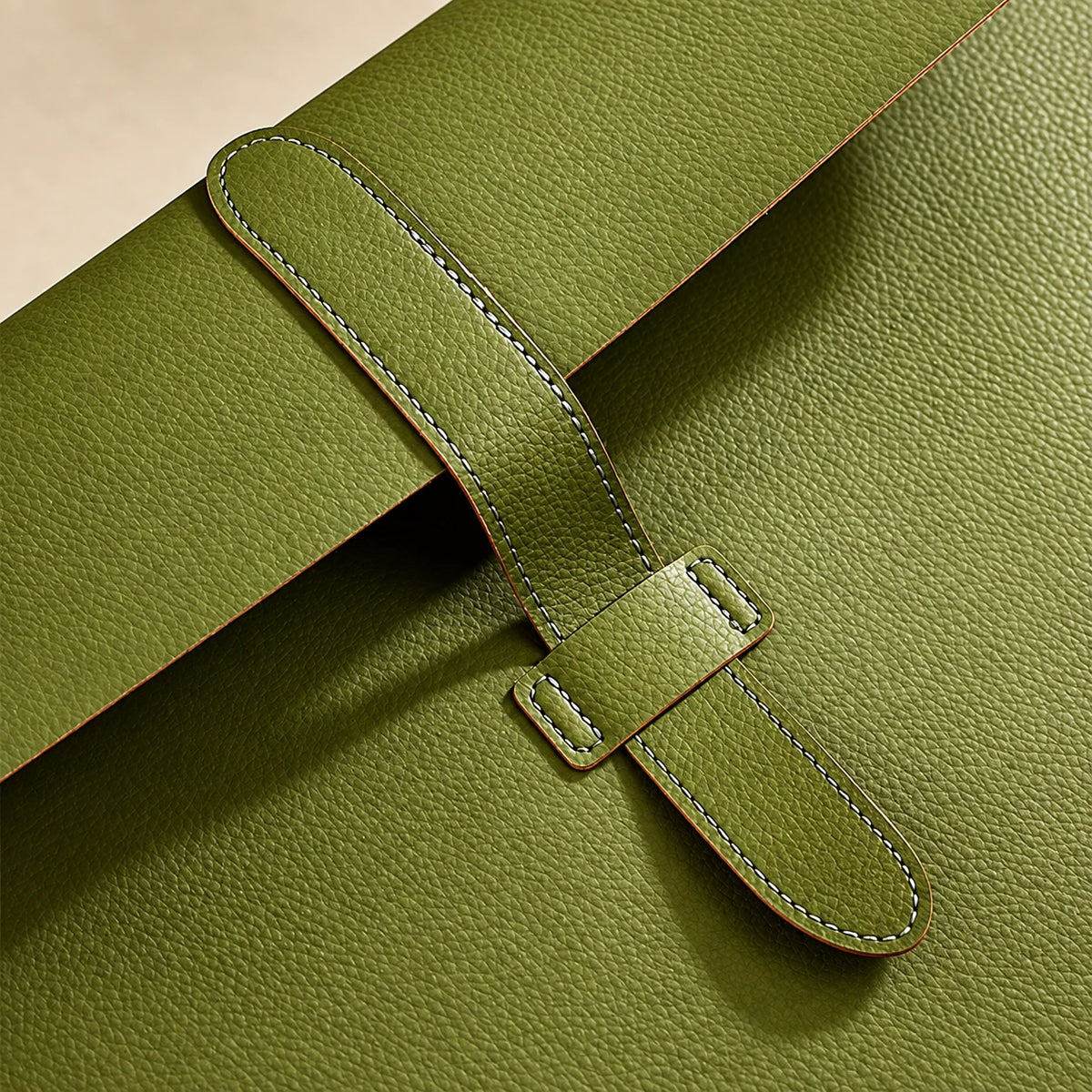 Gros plan sur la lanière de fermeture de la pochette porte-document en similicuir vert olive