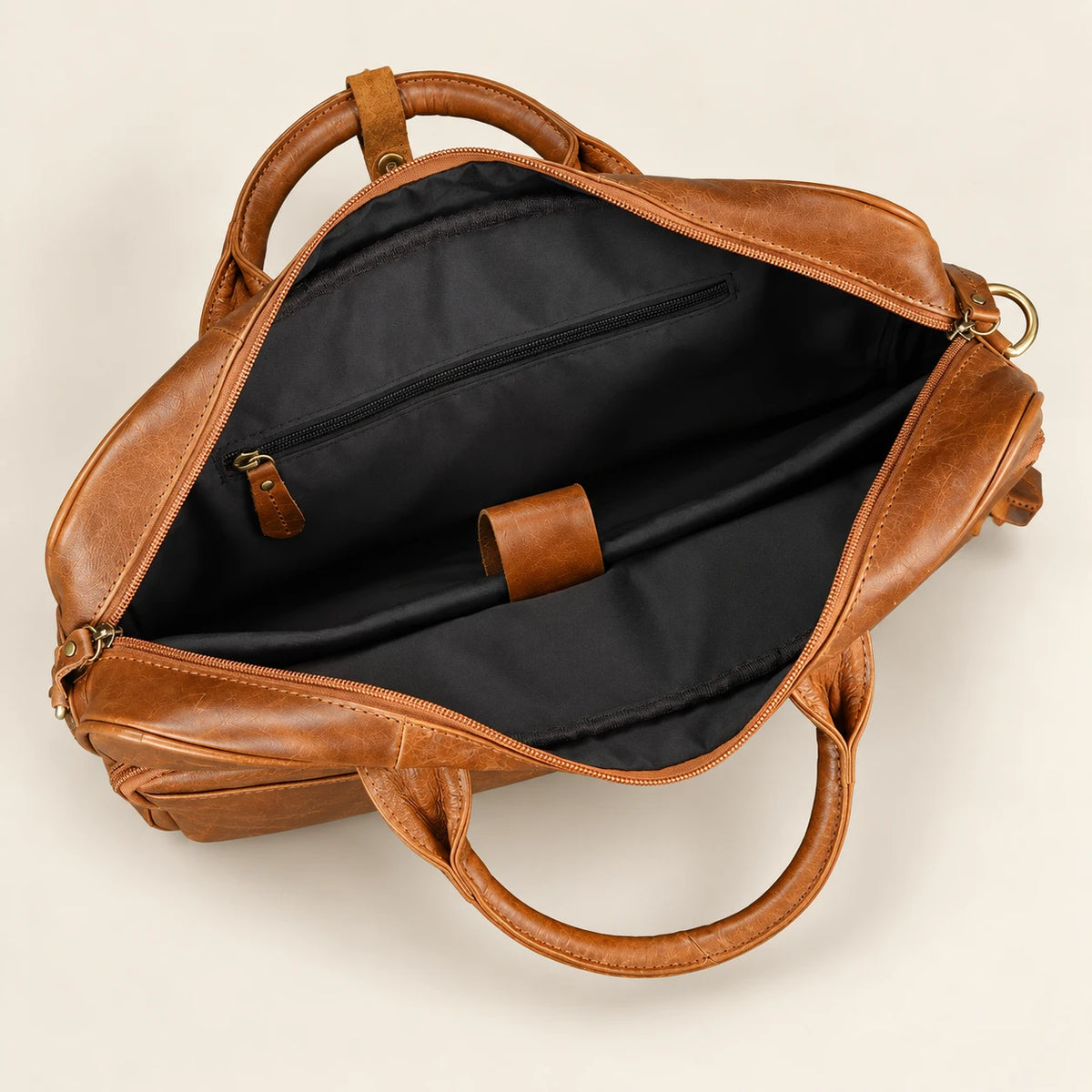 Intérieur principal de la sacoche en cuir camel, compartiment ordinateur et poches visibles