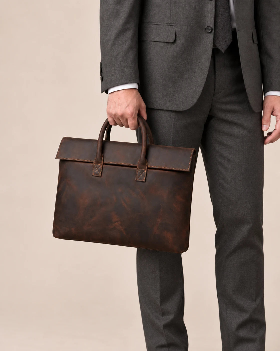 Pochette en cuir marron foncé à rabat portée à la main
