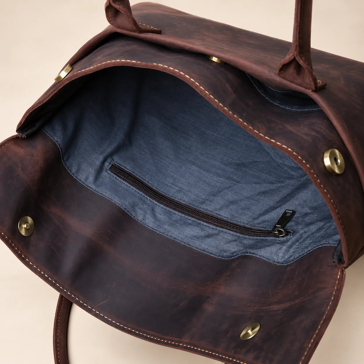 Intérieur de la pochette en cuir marron foncé à rabat, poche zippée visible