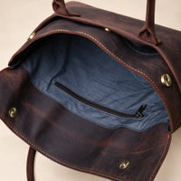 Intérieur de la pochette en cuir marron foncé à rabat, poche zippée visible